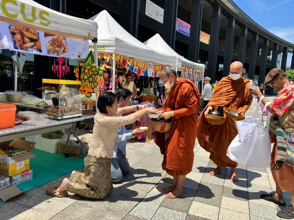 信者の方からの食の寄進を受けるタイから来日している仏教僧侶たち。